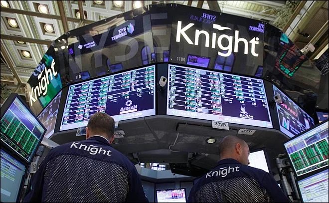 Two traders in Knight jackets on a trading floor, beneath screens showing the Knight logo